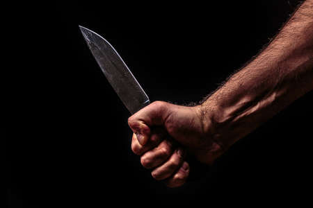 Hunting knife in hand on dark backgroundの写真素材