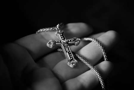 hand holding carved cross over black backgroundの写真素材