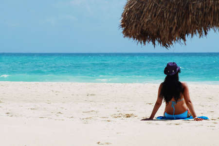beautiful brunette tanning at white sandy beachの写真素材