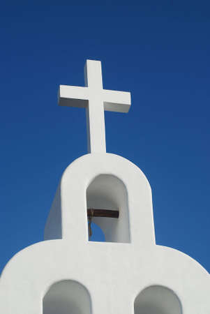 white sandstone church with cross over blue skyの写真素材