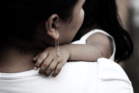 mother holding her child, earrings on childs handの写真素材