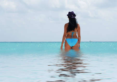 beautiful brunette walking in the sea watching oceanの写真素材