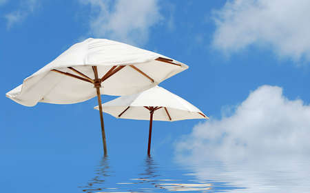 two white parasols on the sea and reflection of skyの写真素材