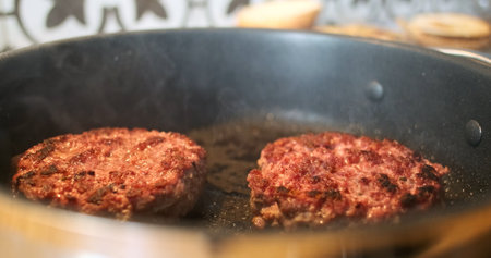 Ready two burger patties in a frying pan. Smoke, close-up, well-roasted beef meat with a crust. Home cooking hamburger.の写真素材