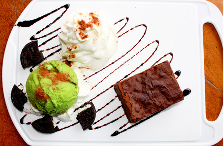 dessert made of brownie and green tea ice cream together with whipped cream on the white plateの写真素材