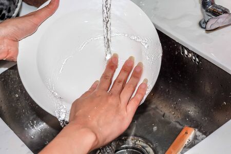 washing white dish with pouring waterの写真素材