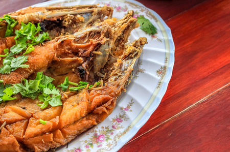Close up Deep Fried Sea Bass With Fish Sauce (Pla Ga Pong Tod Nam Pla) in the plate decorate with coriander parsley leafsの写真素材