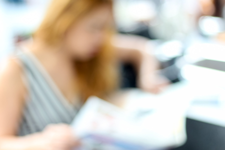 Blurred unrecognized woman reading newspaper in the shop cafeの写真素材