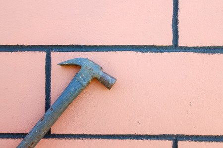 Closeup steel hammer over the stone brick wall backgroundの写真素材