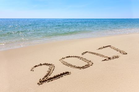 Year 2017 written at the sand beach with sea wave waterの写真素材