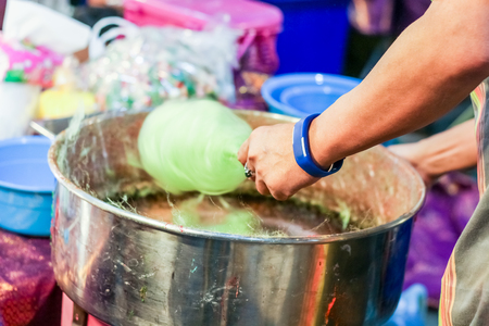 Hand rolling cotton candy in candy floss machineの写真素材
