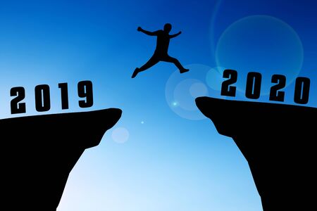 Silhouette young man jumping from 2019 to 2020 yearsの写真素材