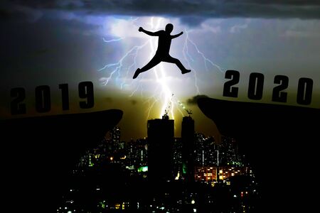 Silhouette young man jumping from 2019 to 2020 yearsの写真素材