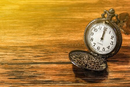 luxury vintage black pocket watch on wooden table, abstract for time concept with copy space, sepia...
