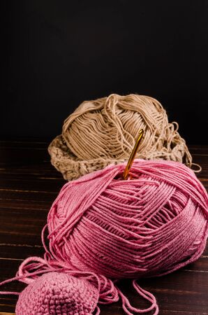 crochet with two ball of yarn on wooden board with black backgroundの写真素材