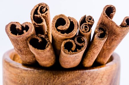 close up of cinnamon on wooden bowl isolated on whiteの写真素材
