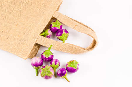 Group of fresh purple eggplant from sack bag backgroundの写真素材
