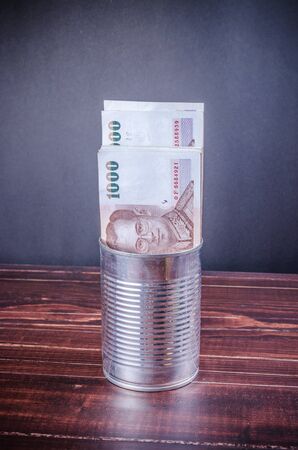 thai banknote in silver can on wooden backgroundの写真素材