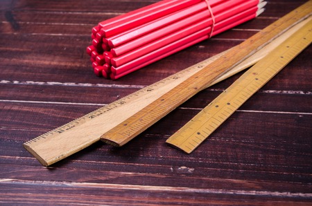 Retro wooden ruler and red wooden pencil on wooden boardの写真素材