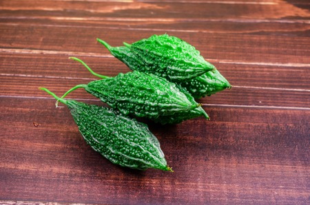 wild bitter gourd, Balsam apple, Balsam pear, Bitter cucumber or Bitter gourd on wooden board backgroundの写真素材
