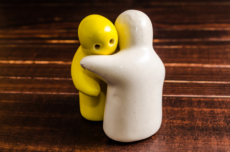 concept abstract of hugging ceramic dolls on wooden tableの写真素材
