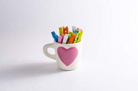 Group colorful pastel of wooden clothespins in coffee cup  isolated on white backgroundの写真素材