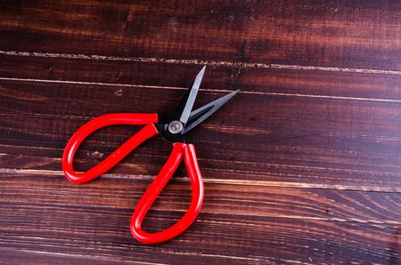 Red scissor on wooden board background