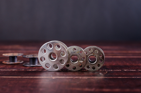 old sewing machine bobbins on wooden backgroundの写真素材