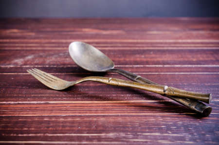 old brass spoon and fork on wooden boardの写真素材
