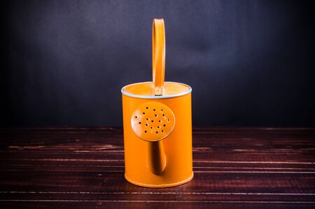 orange garden watering can on wooden board backgroundの写真素材
