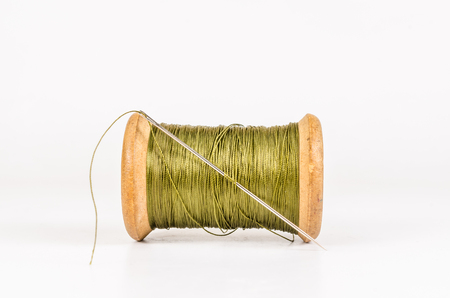 Vintage wooden green thread spool with needle isolated on white background