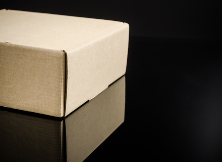 Brown cardboard box on black background with reflectionの写真素材