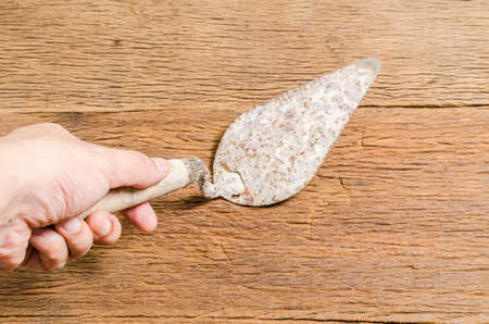 Old rusty trowel tools with hand on wooden boardの写真素材