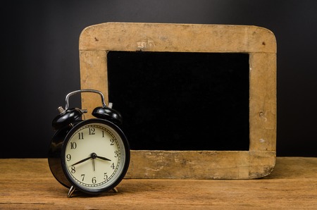Retro alarm clock with chalkboard on wooden table,education concept