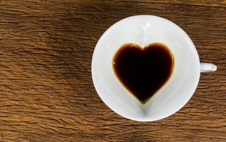 heart shape of black Coffee cup on wooden tableの写真素材