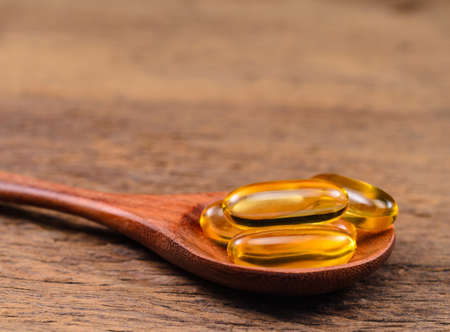 fish oil with wooden spoon on wooden board backgroundの写真素材