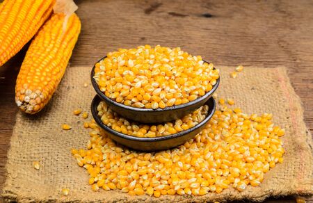 Dried corn seeds in black ceramic bowl on wooden board,agriculture productの写真素材