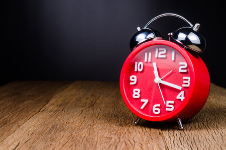 Retro red alarm clock on wooden table with Black backgroundの写真素材