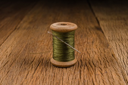 vintage wooden spool thread with needle on wooden boardの写真素材