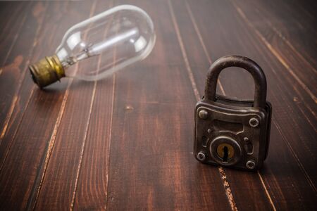 Old padlock and light bulb on wooden board background,block ideaの写真素材
