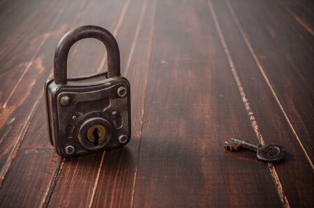 Old padlock on wooden board background