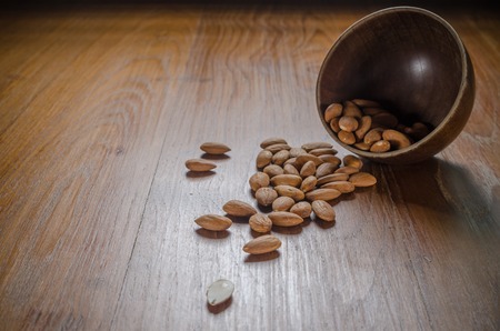 heap of almond from wooden bowl on wooden boardの写真素材