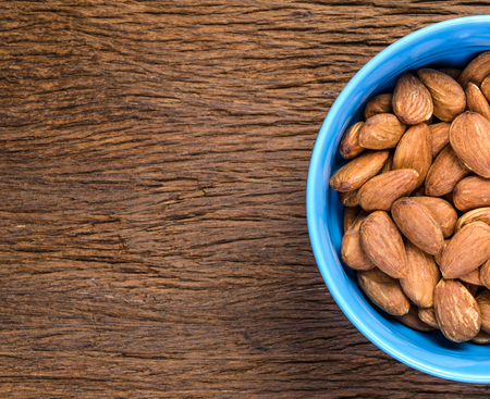 almond in blue porcelain bowl on wooden board backgroundの写真素材