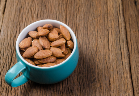 almond in blue porcelain cup on wooden board backgroundの写真素材