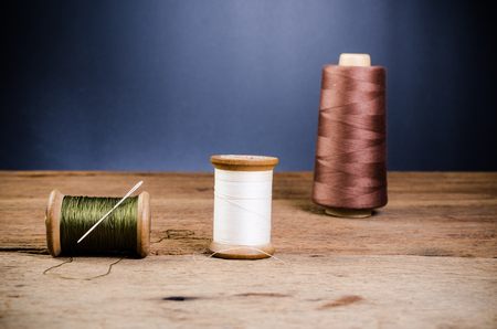 vintage wooden spool thread with needle on wooden board
