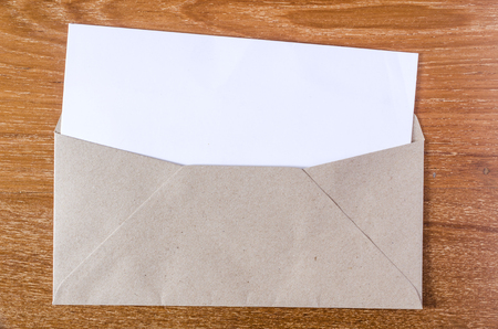 Blank notepad and brown envelope on wooden board backgroundの写真素材