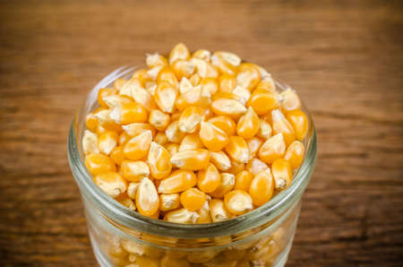 dried corn seeds in glass on wooden board,agriculture productの写真素材