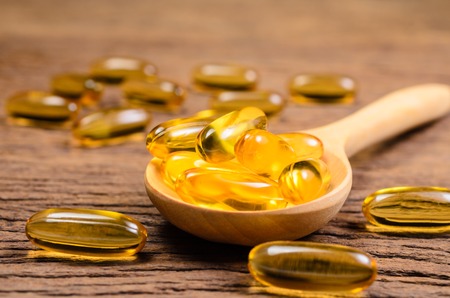 fish oil with wooden spoon on wooden board backgroundの写真素材