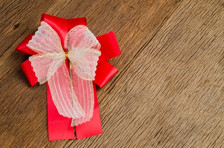 red ribbon gift bow on wooden board background,satin bowの写真素材