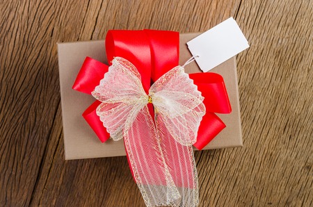 brown gift box with white bow with tag on wooden board backgroundの写真素材